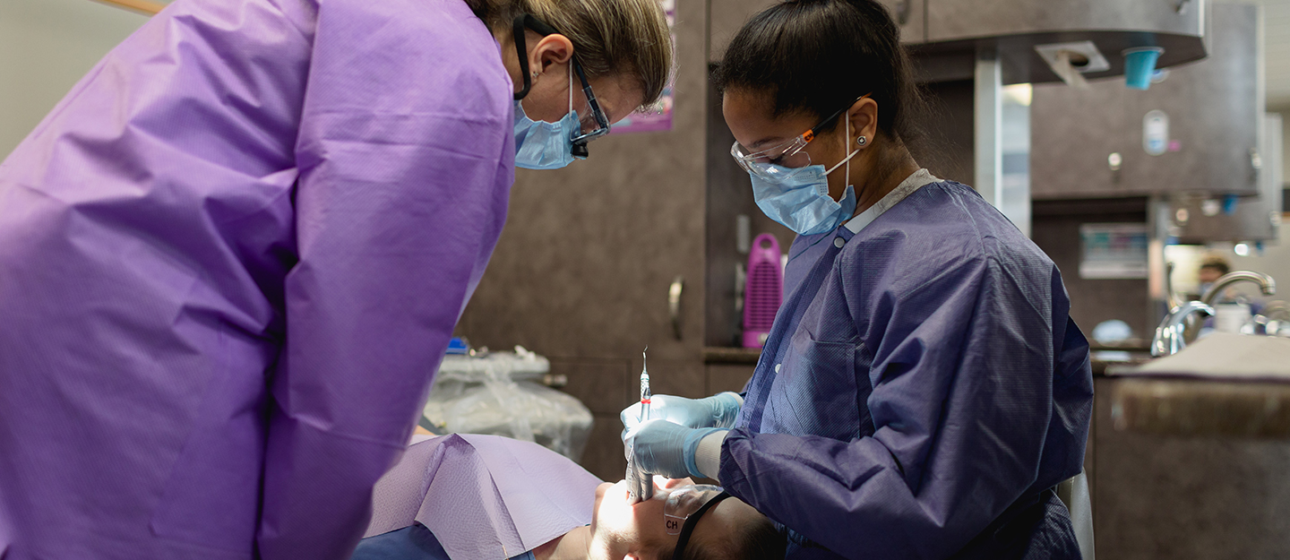 dental student cleaning a patient's teeth