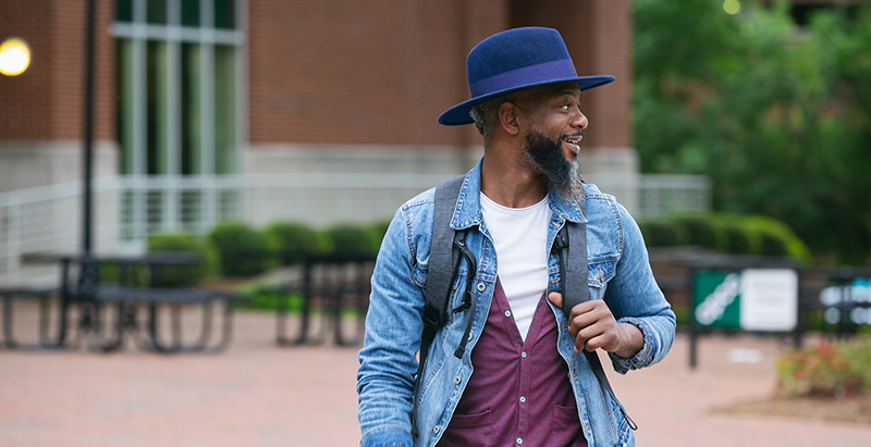 adult student on campus wearing a hat