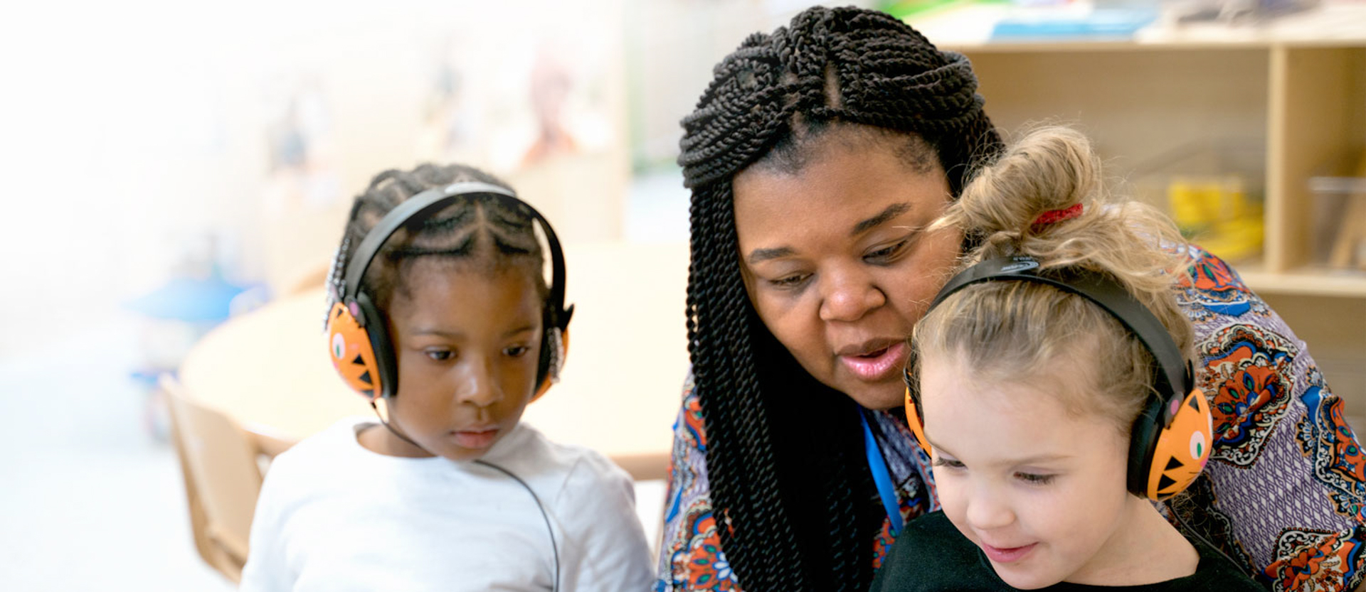 early childhood education student reading with two young children wearing headphones