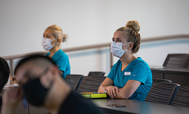 Respiratory therapy students wearing scrubs and masks in class