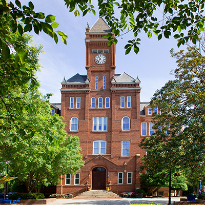 brick clock tower building centered between leafy trees at Johnson C. Smith university