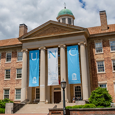 old building on UNC Chapel Hill campus with UNC banner hanging from top of awning