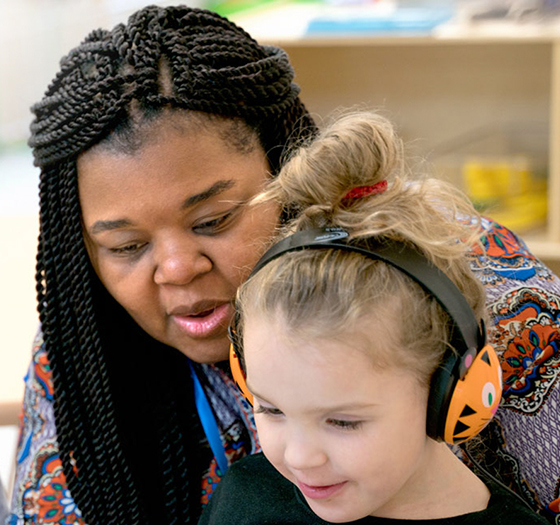 early childhood education student reading with a young child wearing headphones