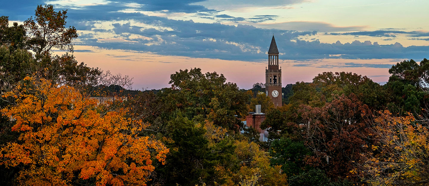 overhead shot of the UNC Chapel Hill belltower at dusk surrounded by fall trees