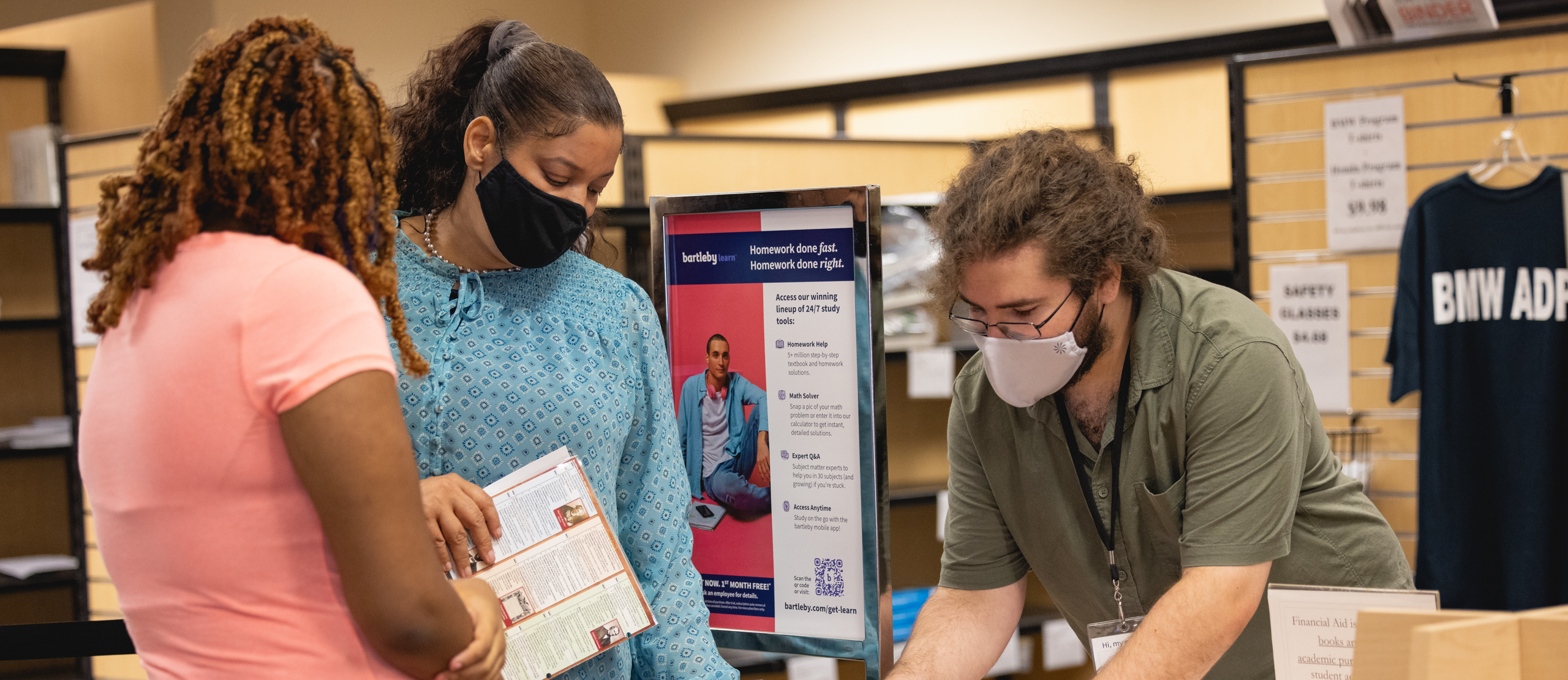 bookstore staff member helping two students