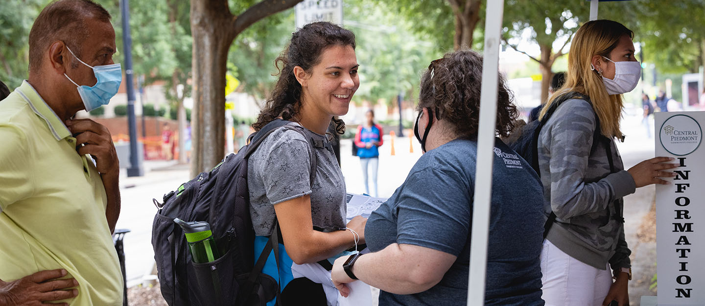 Central Piedmont student engagement staff member helping a smiling student on Central Campus