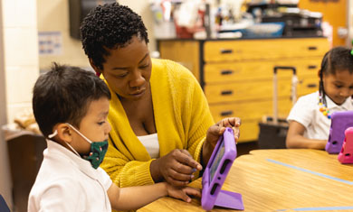 Toye working with student on tablet in classroom