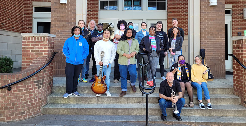 Central Piedmont jazz students sitting on outside steps with their instruments