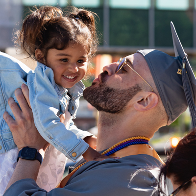 Graduate kissing young daughter after graduating