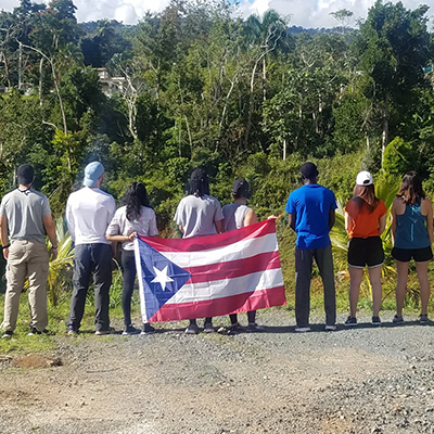 group of Central Piedmont students with their backs to the camera holding a flag.