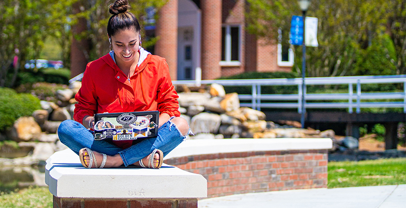 Wingate University and Central Piedmont diverse student sitting outside on laptop