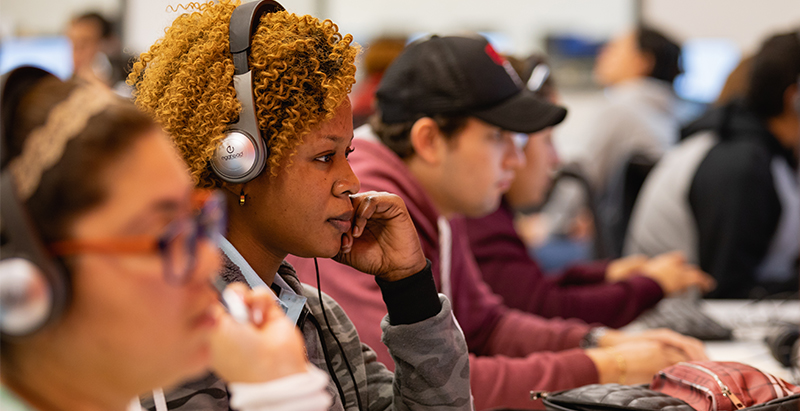 diverse college and career promise students with headsets in front of computers 