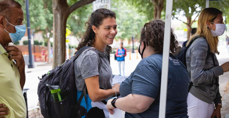 Central Piedmont student engagement staff member helping a smiling student on Central Campus