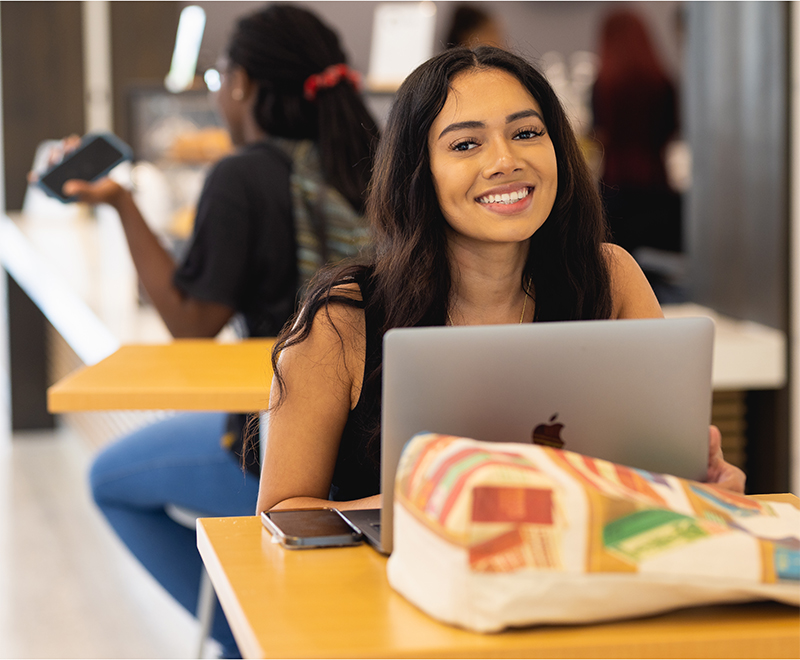 diverse student at the Parr Center smiling with her laptop