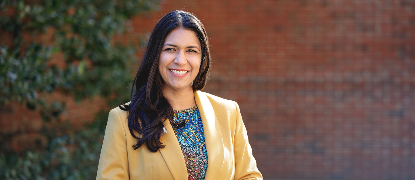 Information Technology student smiling in front of camera with yellow blazer on