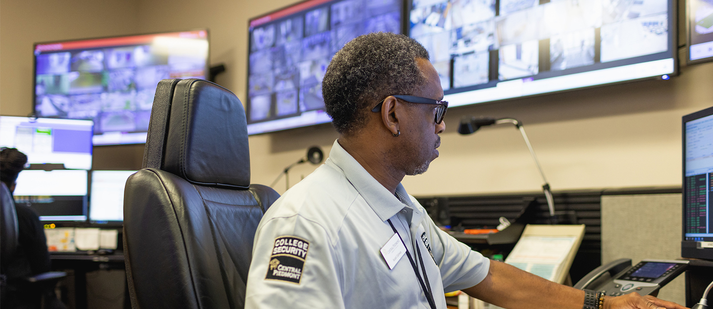 Central Piedmont college security diverse staff member at desk looking at security monitors