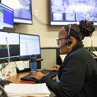 Central Piedmont college diverse security staff member at desk with headset looking at security monitors