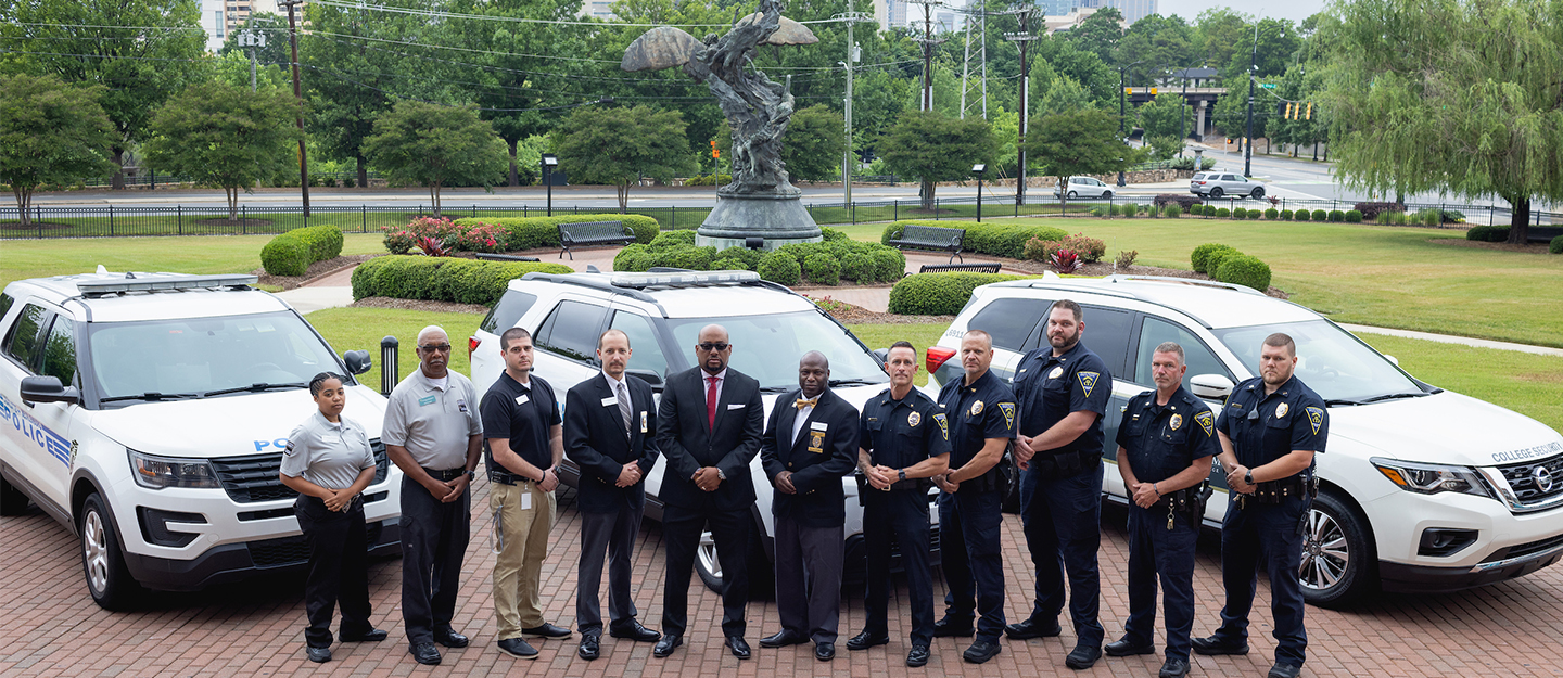 Central Piedmont security officers in uniform standing outside in front of security vehicles