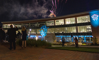 Central Piedmont Parr Center lit up at night with fireworks over head and people watching