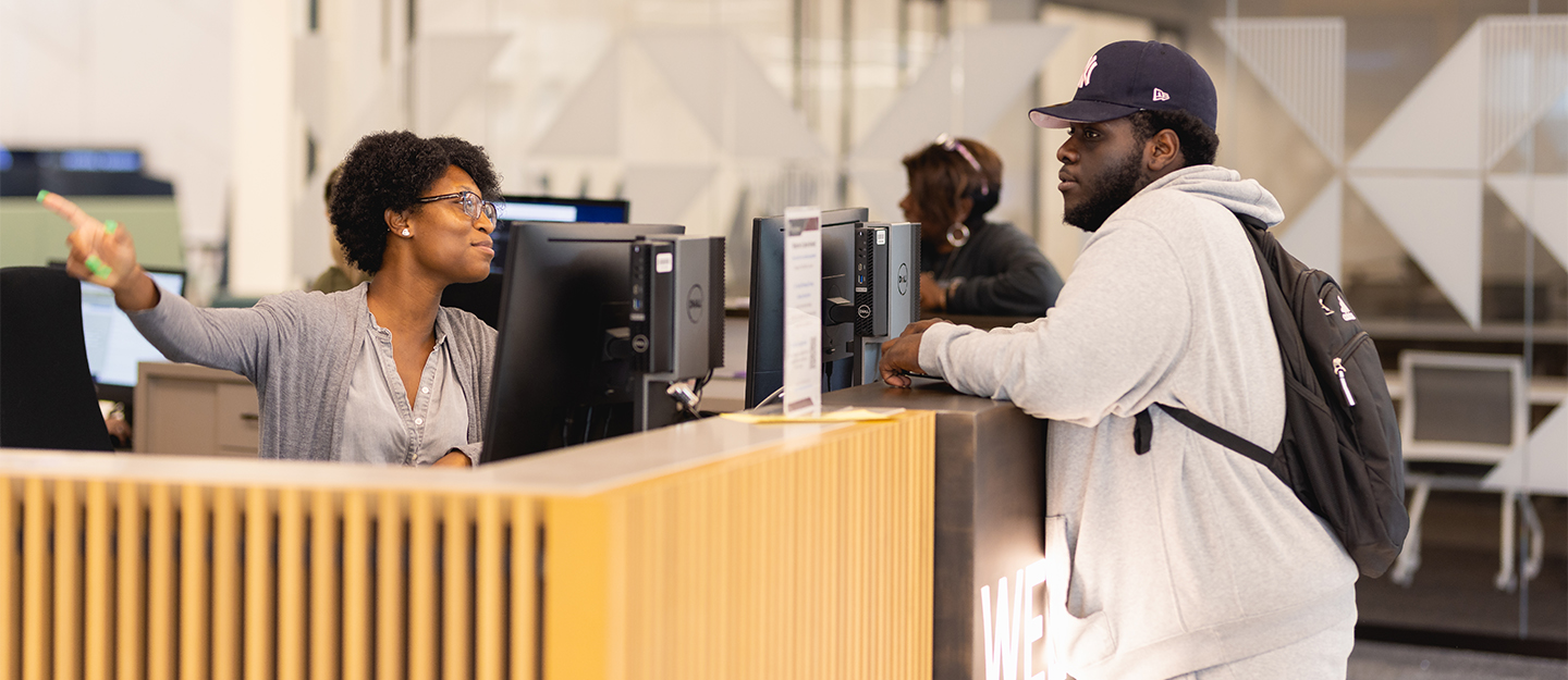 diverse staff member helping diverse student at Welcome Center desk in the Parr Center