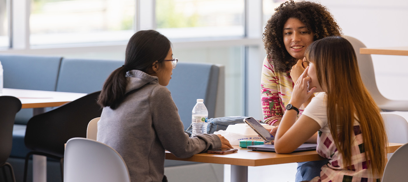 diverse students seated at a table talking at the Parr Center on campus 