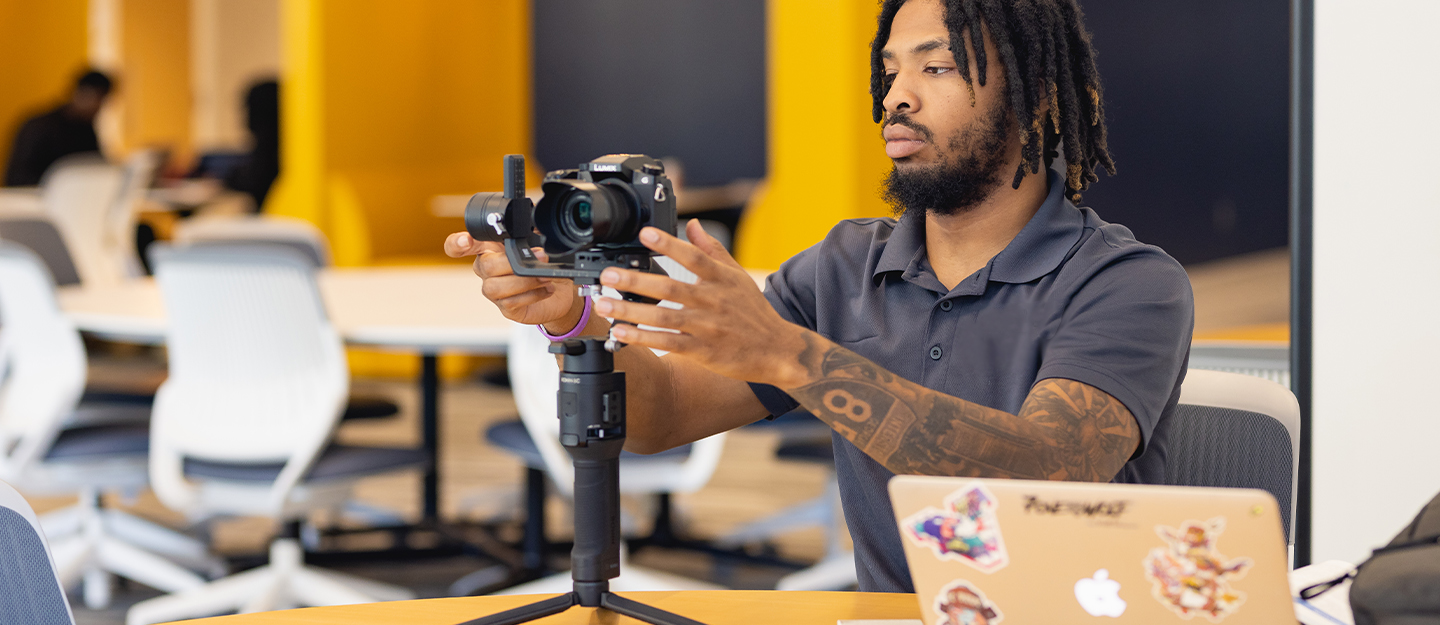 A male student working with a digital camera on a tripod