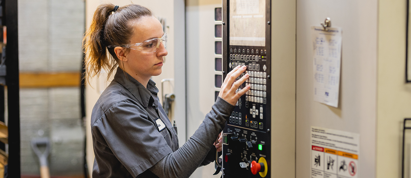 computer integrated machining student pushing buttons on a wall device