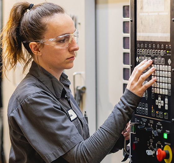 computer integrated machining student pushing buttons on a wall device