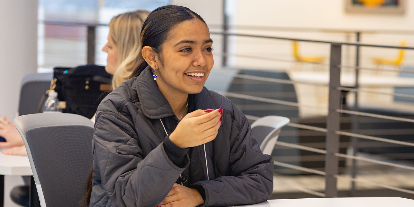 A student with her hair in a ponytail smiling at the camera