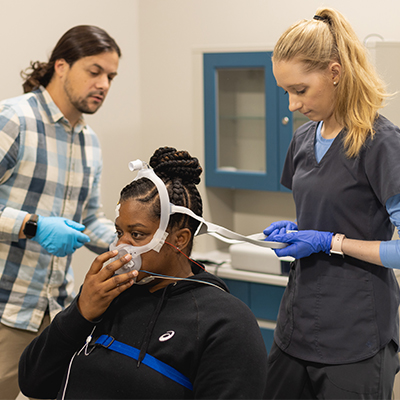 polysomnography sleep study student patient with CPAP machine over her nose facing students