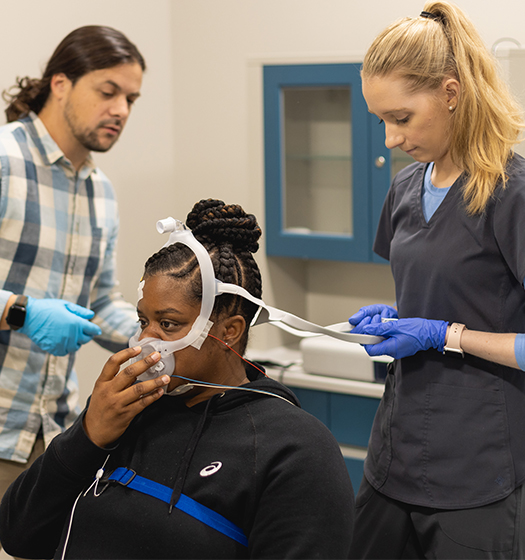 polysomnography sleep study student patient with CPAP machine over her nose facing students