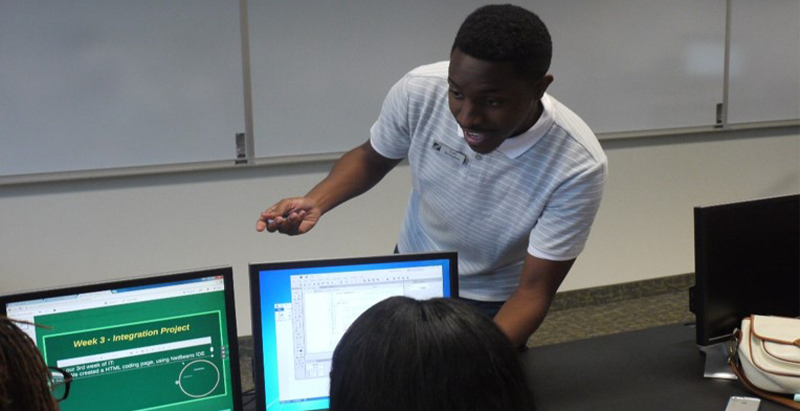 Student teaching other students on a computer 