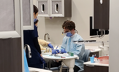 Dental students assist a patient in a dental chair