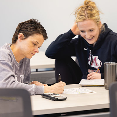 Two Central Piedmont students using a calculator in a classroom