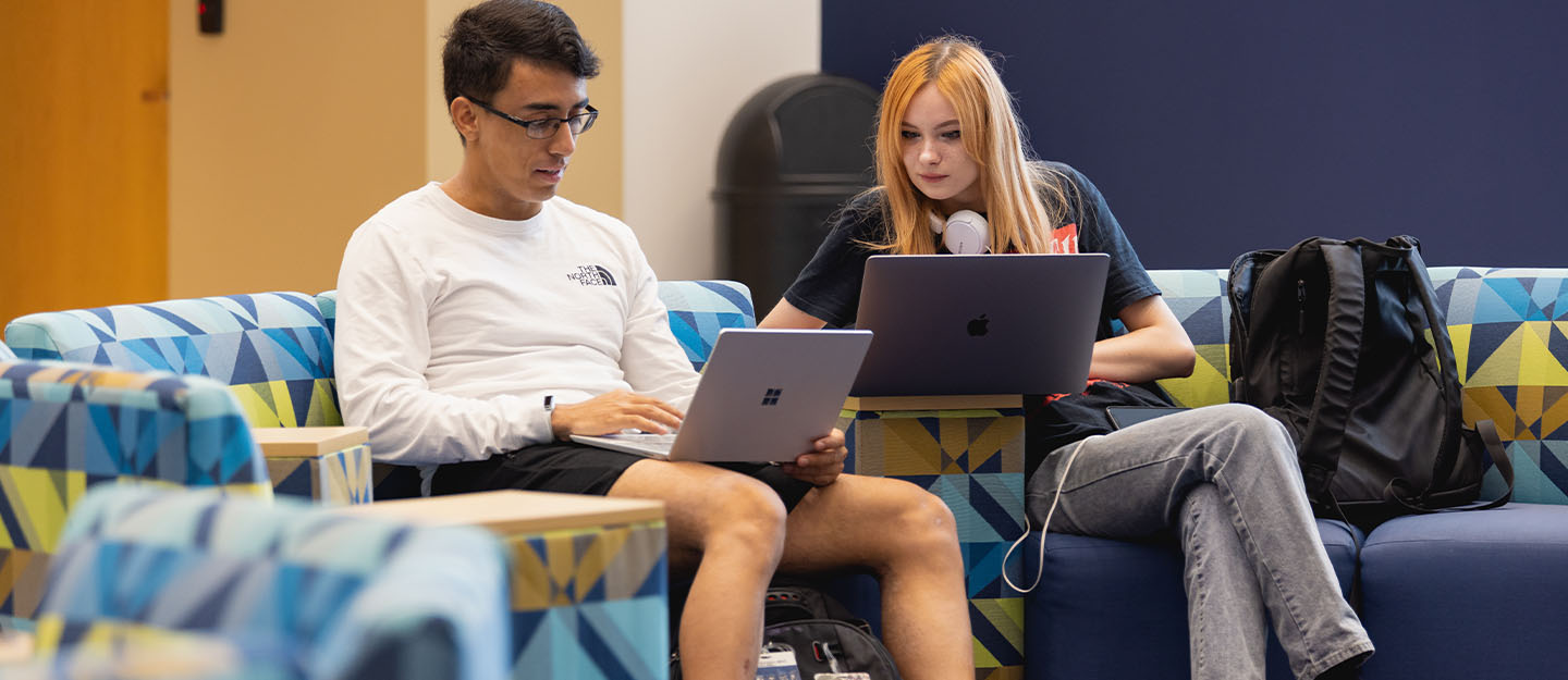 Two Central Piedmont students working on their laptops on the Levine Campus