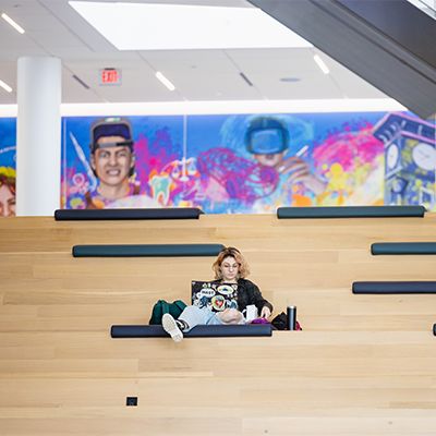 Student sitting on inside Parr steps with laptop 