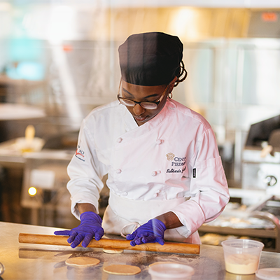 Culinary person rolling out dough in chef's coat 