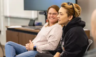 Two students sit casually and talk.