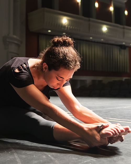 performing arts student sitting on floor of stage of Halton Theater