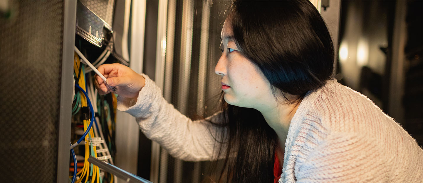 information technology 2 student in networking closet holding networking cables