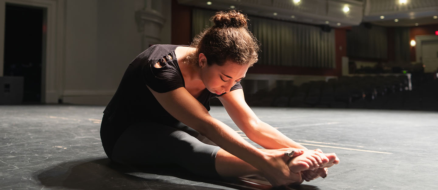 performing arts student sitting on floor of stage of Halton Theater