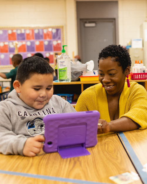 instructor smiling at student looking at tablet inside a classroom at Central Piedmont Community College