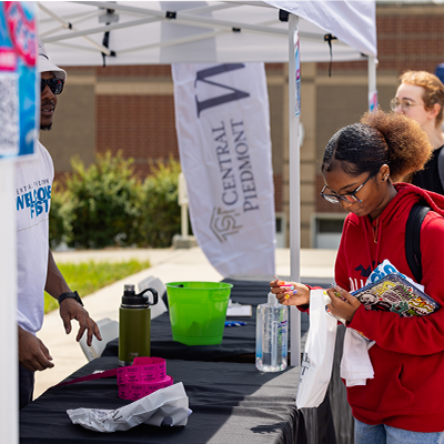Student picking up a t-shirt from a Welcome Week table 