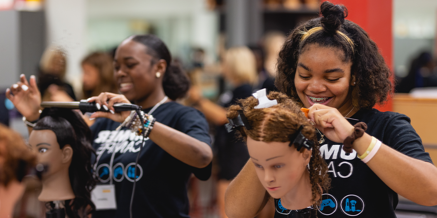 Camp attendees practicing hairstyles on manikin heads 