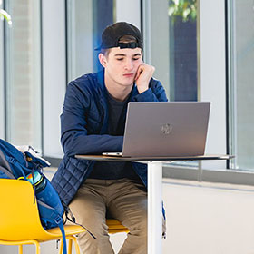 A Central Piedmont student in the library with an HP laptop