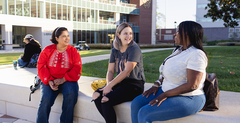 Three students sitting on the Quad