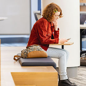 A Central Piedmont student looking at a smartphone in the library