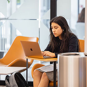 A Central Piedmont student working on a Macbook in the library