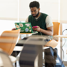 A Central Piedmont student working on a laptop with a green cover