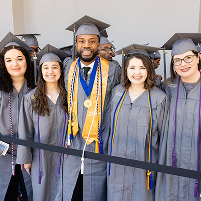 Central Piedmont graduates in gray cap and gown and honor cords 